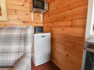 a room with a bed and a refrigerator and a tv at Mill Cabin Denant in Haverfordwest