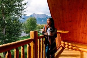 a woman sitting on a balcony looking out over a river at Miette Mountain Cabins in Jasper