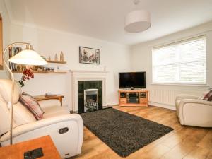 a living room with a fireplace and a tv at Riverside Cottage in Cockermouth