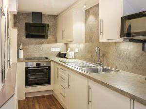 a kitchen with white cabinets and a sink at Beech Tent Lane Cottage in Kelso