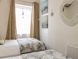 1 dormitorio con cama y espejo en Beech Tent Lane Cottage, en Kelso