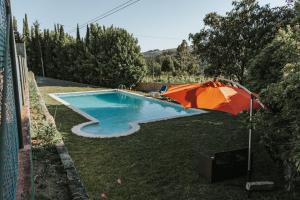 an orange umbrella sitting next to a swimming pool at Casa dos Vales - Luxury Villa in Penafiel