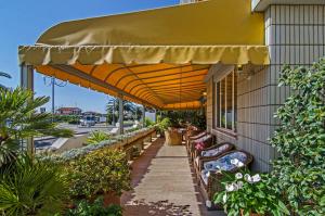 un patio con bancos y una sombrilla en un edificio en Hotel Alk, en Marina di Pietrasanta