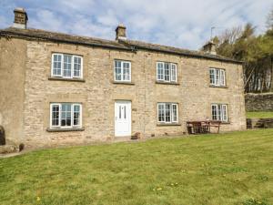 an old stone house with a grassy yard in front of it at Sunnyside Cottage in Stainton
