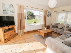 a living room with a tv and a couch and a table at Nant y Gof in Holyhead
