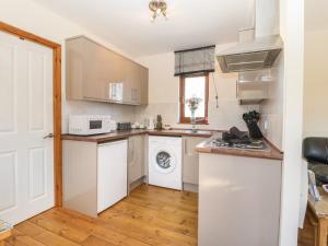 a kitchen with white cabinets and a washer and dryer at Cherry Lodge in Watchet