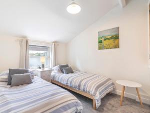 1 dormitorio con 2 camas, mesa y ventana en Riverstone Cottage, en Skipton