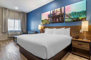 Un dormitorio con una gran cama blanca y una pared azul en Clarion Pointe Port Arthur-Beaumont South, en Port Arthur