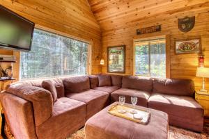 a living room with a brown couch and a tv at Sweet Retreat Cabin in Leavenworth