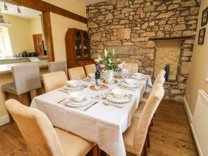 a dining room with a table with chairs and a stone wall at Waingate Cottage in Cark