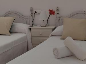 Un dormitorio con 2 camas y una mesa con una flor. en Apartamentos Bolonia - M a n u e l a, en Bolonia