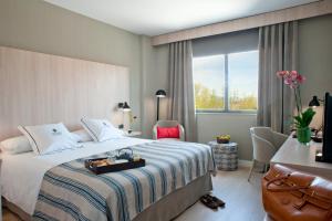 um quarto de hotel com uma cama, uma secretária e uma janela em Aravaca Village Hotel em Madrid