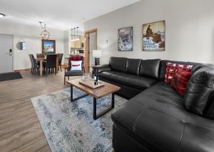 a living room with a black leather couch and a table at Newly Renovated Grizzly Lodge, Spacious 3BR 2BA with open pool, hot tub in Canmore