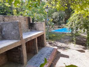 un banco de piedra junto a una piscina en Casa Elisa en Luján de Cuyo