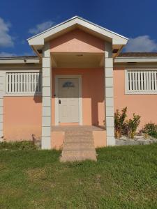 una casa rosa con una puerta blanca en Fishtails Palms, en Stuart Manor