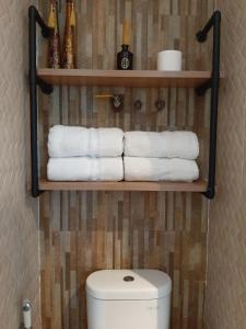 a bathroom with a toilet and a shelf with towels at Panoramic View Grand Kamala Lagoon in Bekasi