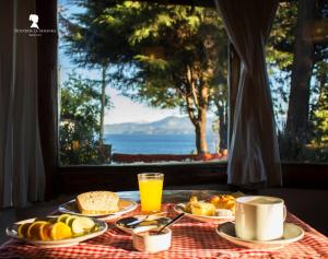 een tafel met ontbijtproducten en uitzicht op de oceaan bij HTL La Malinka in Bariloche