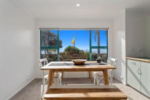 a kitchen and dining room with a table and a window at The Lights House - Beachfront Ohope Holiday Home in Ohope Beach