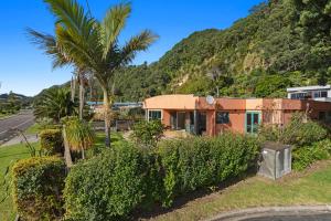 a house on the side of a road with palm trees at The Lights House - Beachfront Ohope Holiday Home in Ohope Beach