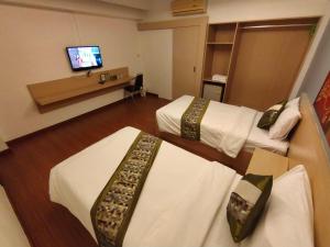 a hotel room with two beds and a television at Aileen Hotel in Khon Kaen