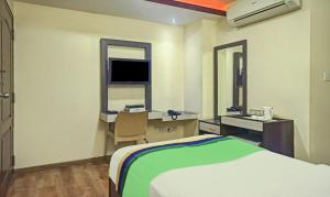 a bedroom with a bed and a desk and a television at Treebo Savoury Sea Shell Residency in Bengaluru