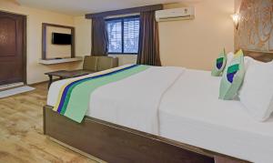 a hotel room with a large bed and a chair at Treebo Savoury Sea Shell Residency in Bengaluru