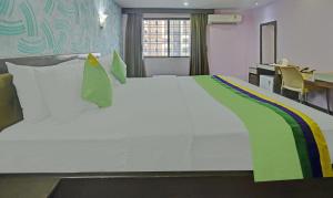 a large white bed in a room with a desk at Treebo Savoury Sea Shell Residency in Bengaluru