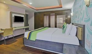 a bedroom with a bed and a desk and a tv at Treebo Savoury Sea Shell Residency in Bengaluru