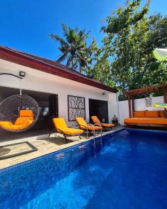 a villa with a swimming pool with yellow chairs at King's Home Villa in Bantul