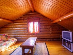 Una sala de estar con un sofá y una ventana en una cabaña de madera. en Chalet de charme avec étang privé : pêche, nature et détente au cœur du Périgord - FR-1-616-72, en Dussac