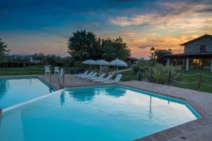a large swimming pool with chairs and a house at Agriturismo Il Cantico di San Francesco in Palazzo