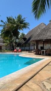 a resort with a swimming pool with a thatch roof at peeKAboo Diani Beach in Diani Beach