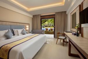 a hotel room with a large bed and a desk at Grand Inna Kuta in Kuta
