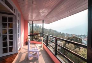 a balcony with a white chair and a view at Tag Along 2 0 Hostel Gangtok in Gangtok