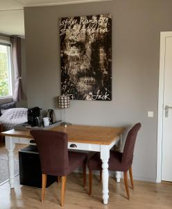 a dining room table with chairs and a painting on the wall at Bed and Breakfast De Paalberg in Hoenderloo