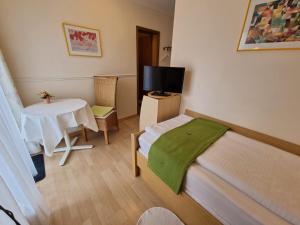 a small room with a bed and a table with a tv at Parkhotel Ruhpolding inklusive Chiemgaukarte in Ruhpolding