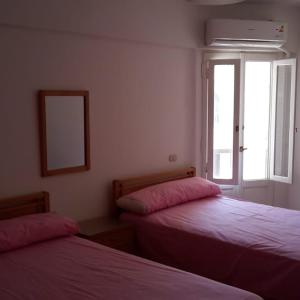 a bedroom with two beds with pink sheets and a window at lazorde Bay in El Alamein