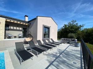 a group of chairs sitting on a patio next to a pool at Villa Anthea Paola in Nedeščina