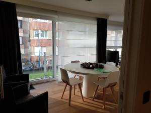 a dining room with a table and chairs and a window at Koksijde Zeedijk LaDigue102 appartement-lateraal zeezicht - baby's niet meer toegestaan in Koksijde