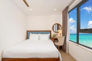 a bedroom with a bed and a desk with a window at Paris Deli Danang Beach Hotel in Danang