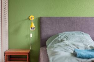 a bed with a yellow lamp next to a green wall at Korinth Bed & Breakfast in Faaborg