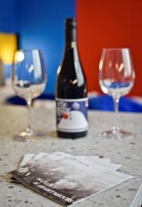 a bottle of wine sitting on a table with two wine glasses at ZACHÁR APARTMAN in Sopron