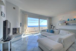 sala de estar con muebles blancos y ventana grande en Villa Ischia Attico sul mare a Verezzi, en Borgio Verezzi