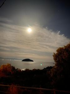 a full moon rising over a body of water at Overwave Apartment in Kavála