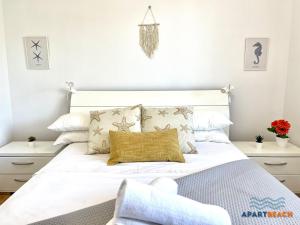 ein Schlafzimmer mit einem großen weißen Bett mit Kissen in der Unterkunft APARTBEACH CYE 6 CLIMATIZADO y JUNTO PLAYA in Salou + 37 Fotos