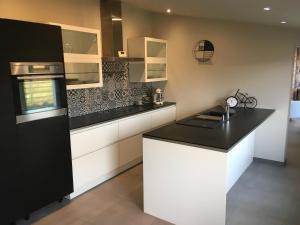 a kitchen with a black counter top and white cabinets at Oase 't Huyseke in Blankenberge