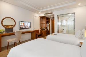 a bedroom with a bed and a desk and a mirror at Paris Deli Danang Beach Hotel in Danang