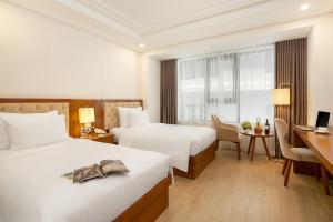 a hotel room with two beds and a desk at Paris Deli Danang Beach Hotel in Danang