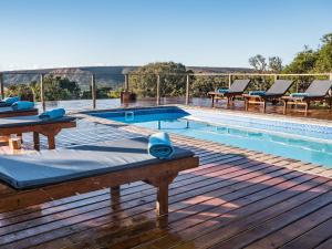 einen Pool mit Tischen und Stühlen auf einer Holzterrasse in der Unterkunft Woodbury Lodge – Amakhala Game Reserve in Amakhala Game Reserve