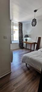 a bedroom with a bed and a desk and a window at Location G&W, très proche sanctuaires in Lourdes